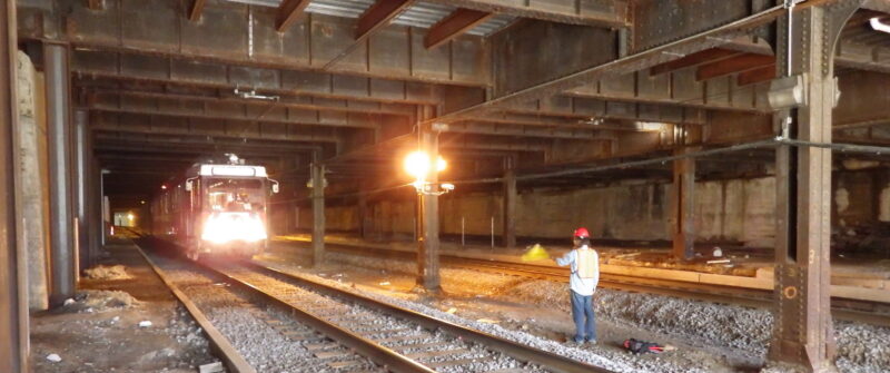 A train passes a construction worker in the Union Station Tunnel.
